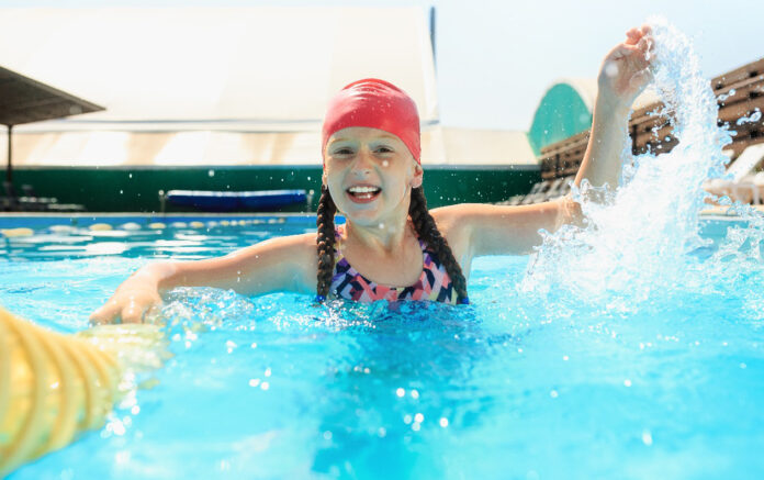 The portrait of happy smiling beautiful teen girl at the pool